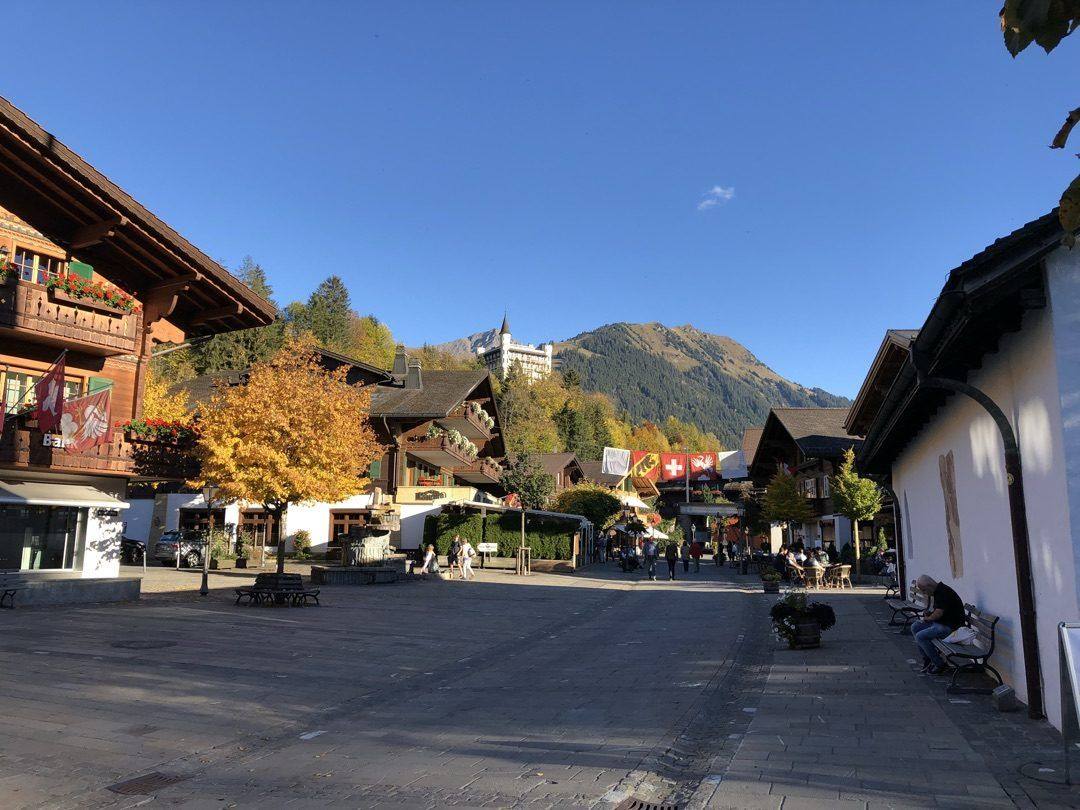 Gstaad Dorfplatz im Herbst mit Palace Hotel und Schweizer Fahnen