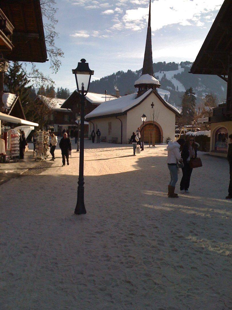 Gstaad Kirche im Winter mit Skipiste im Hintergrund