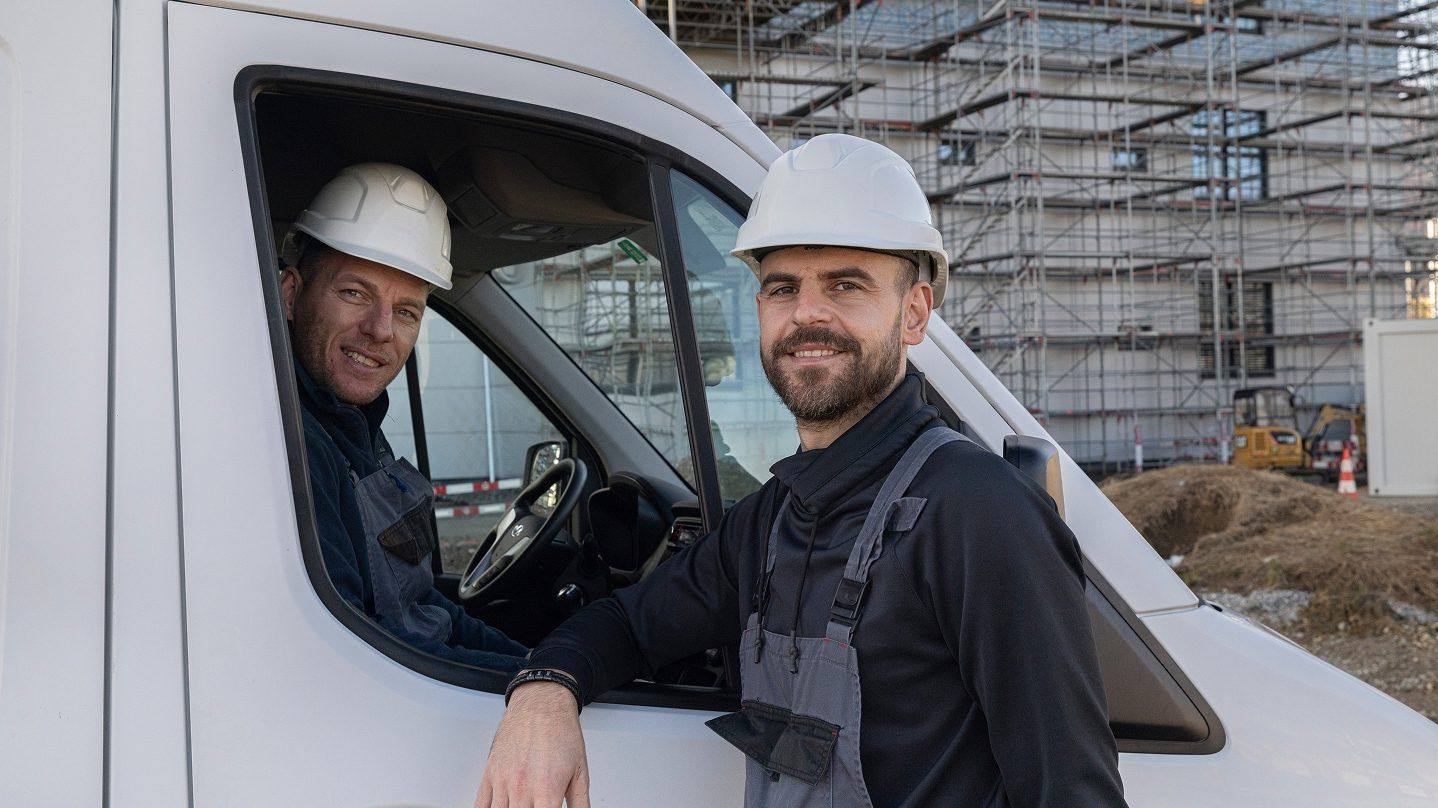 Bonaria-Mitarbeiter mit Helm am Firmenfahrzeug auf der Baustelle