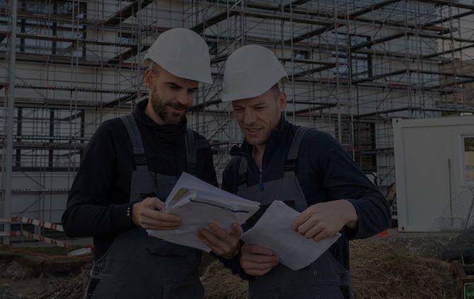 Zwei Bonaria-Mitarbeiter mit Helm besprechen Baupläne